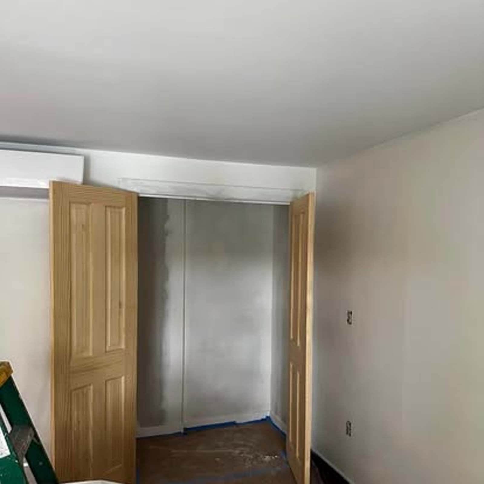 A room with wooden doors and a ladder in it.