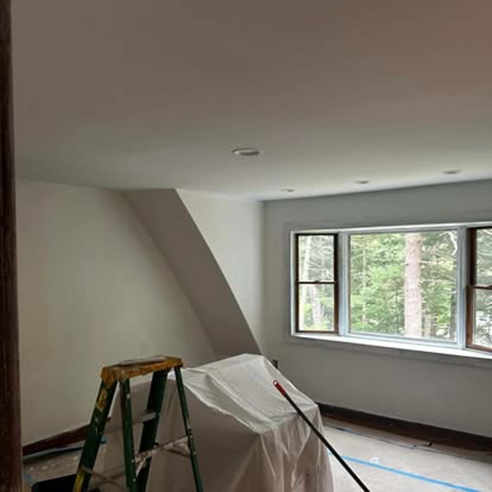 A room with a ladder and a mop in it.