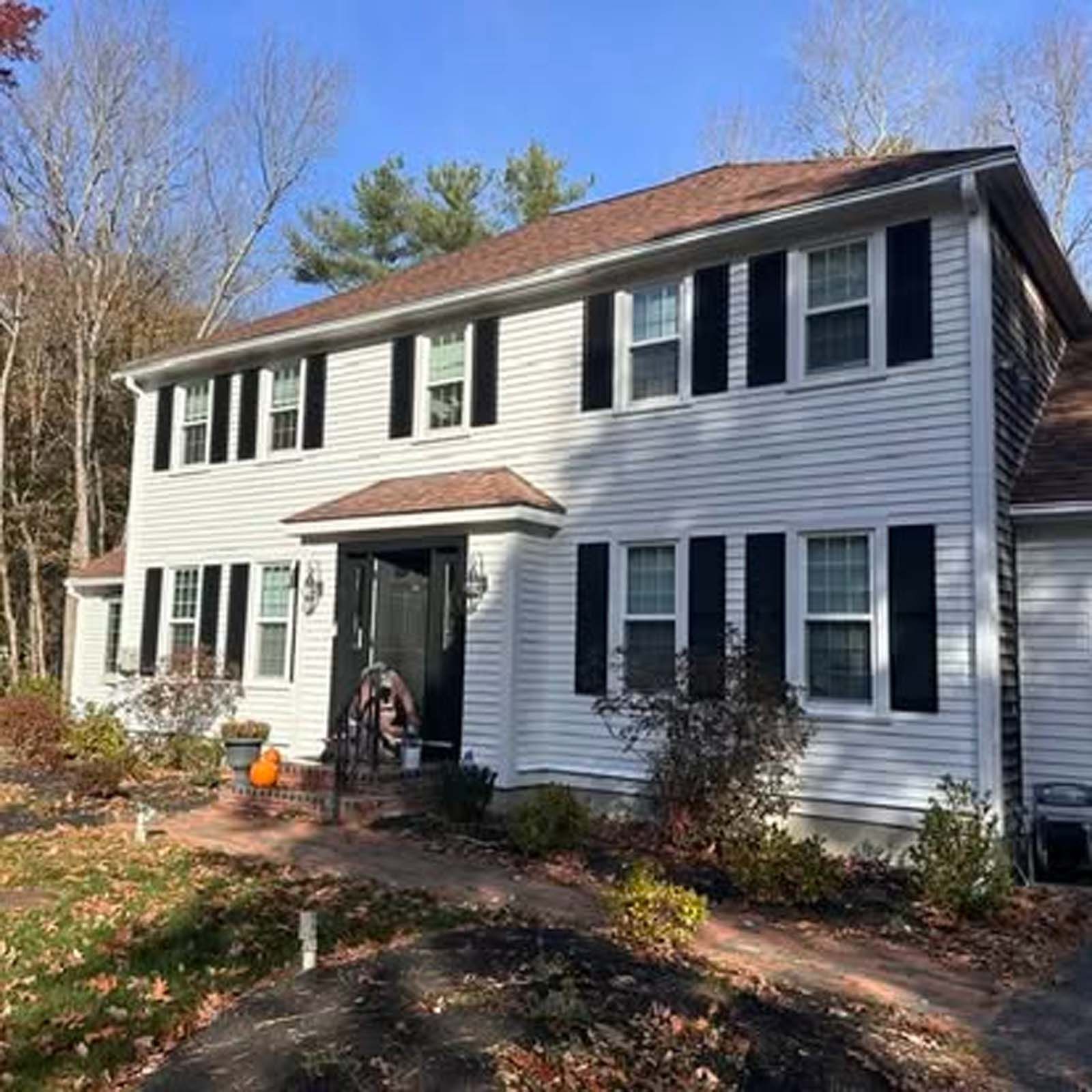 A large white house with black shutters and a brown roof.
