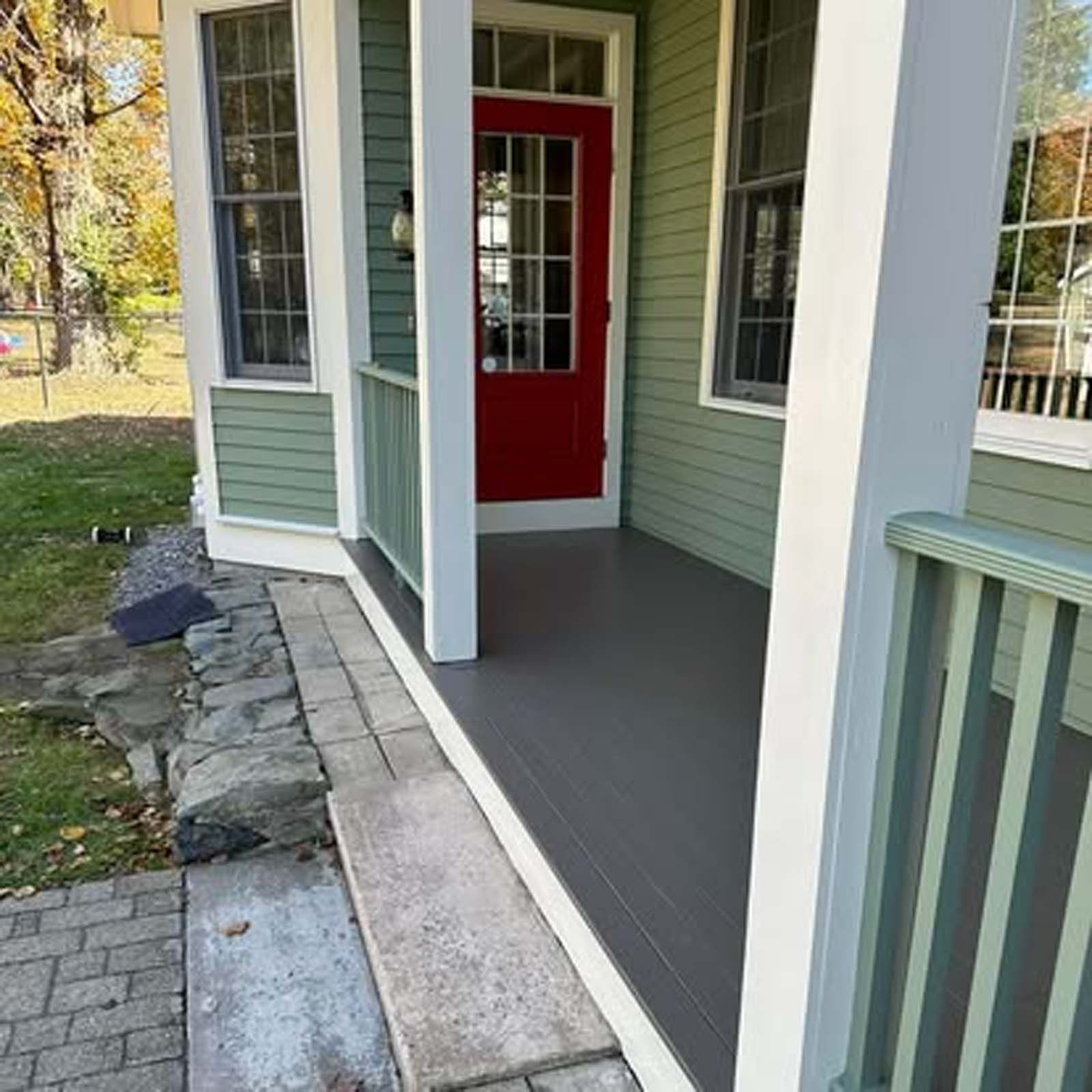 A green house with a red door and a porch
