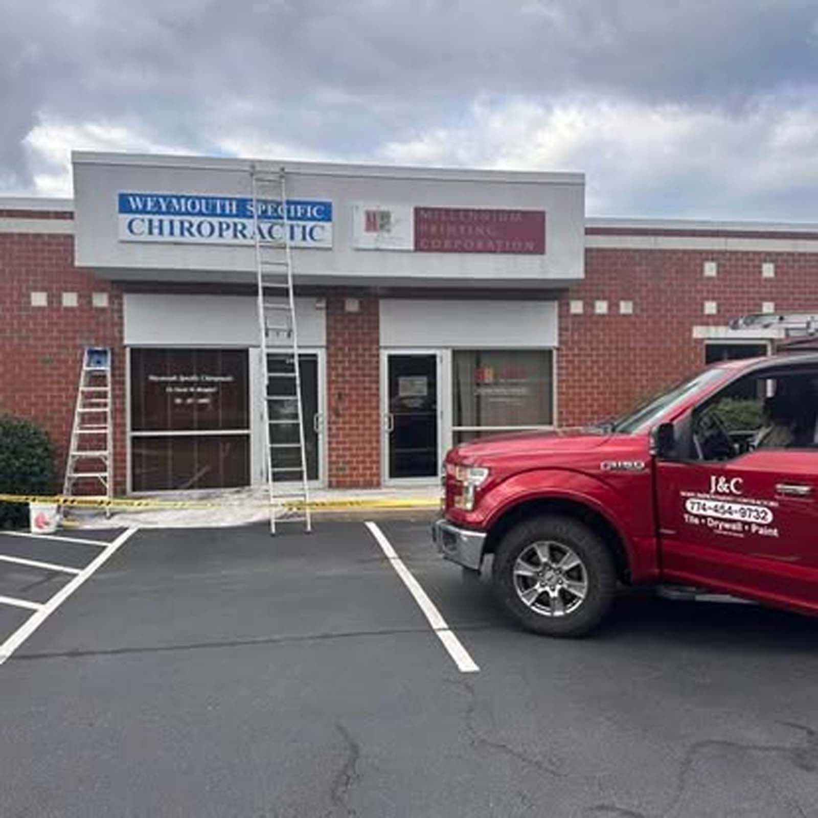 A red truck is parked in front of a chiropractic office.