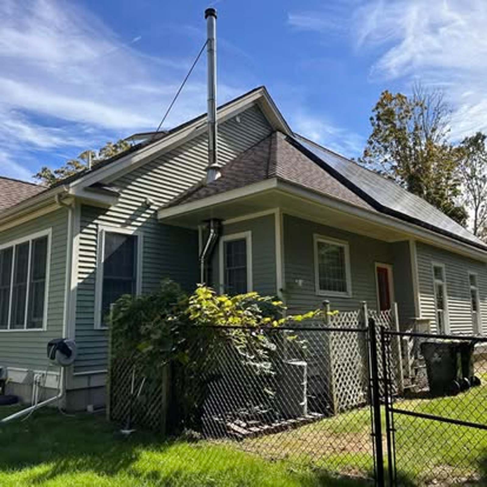 A small house with a fence and solar panels on the roof.