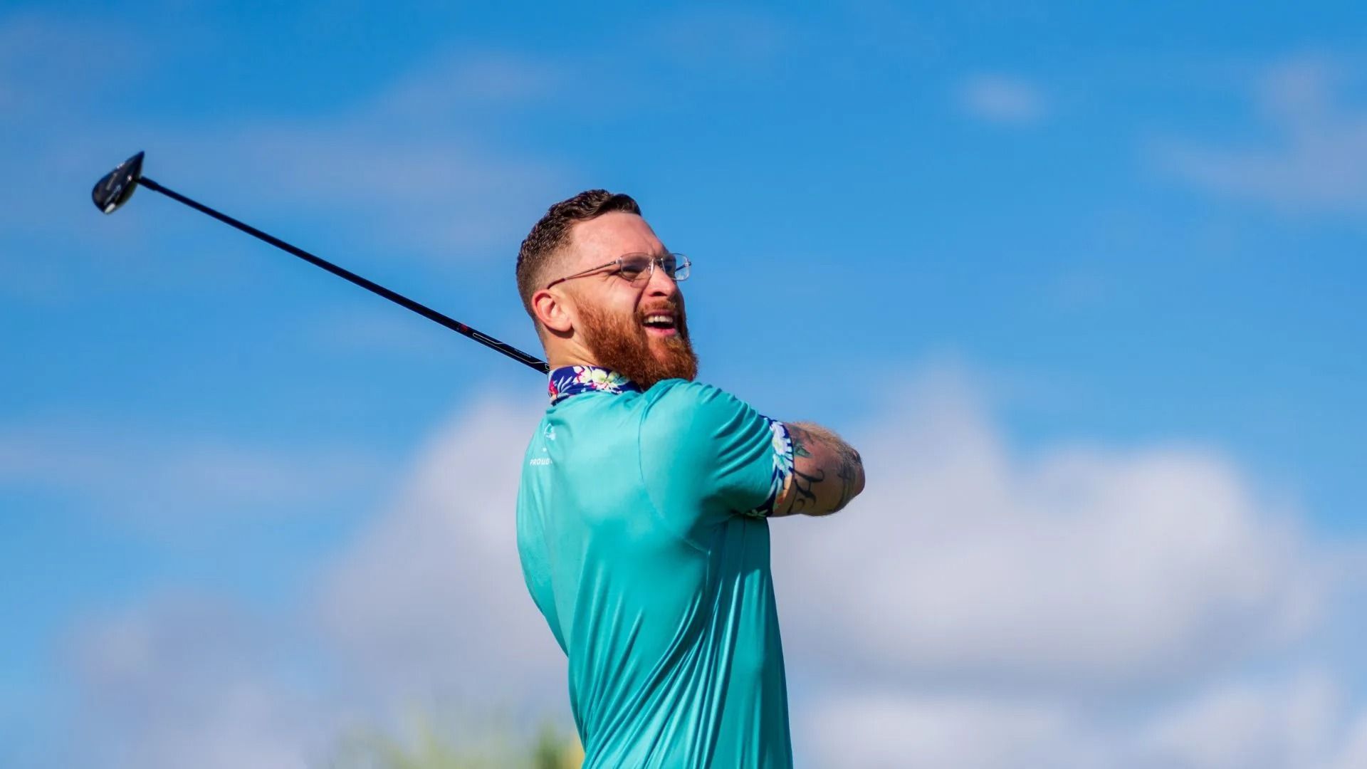 A man is swinging a golf club on a golf course.