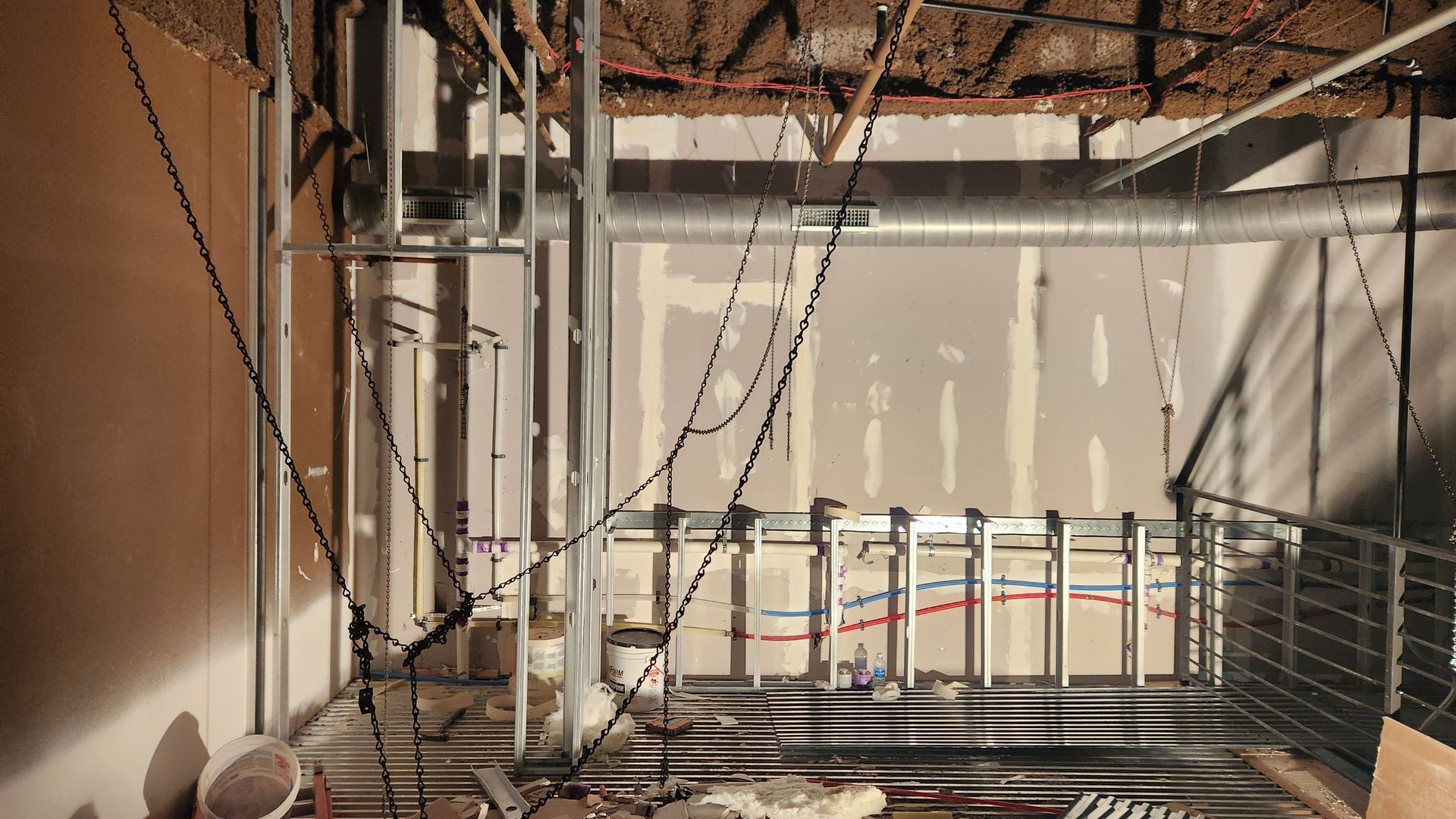 Interior of building under construction; exposed pipes, wires, and ductwork.