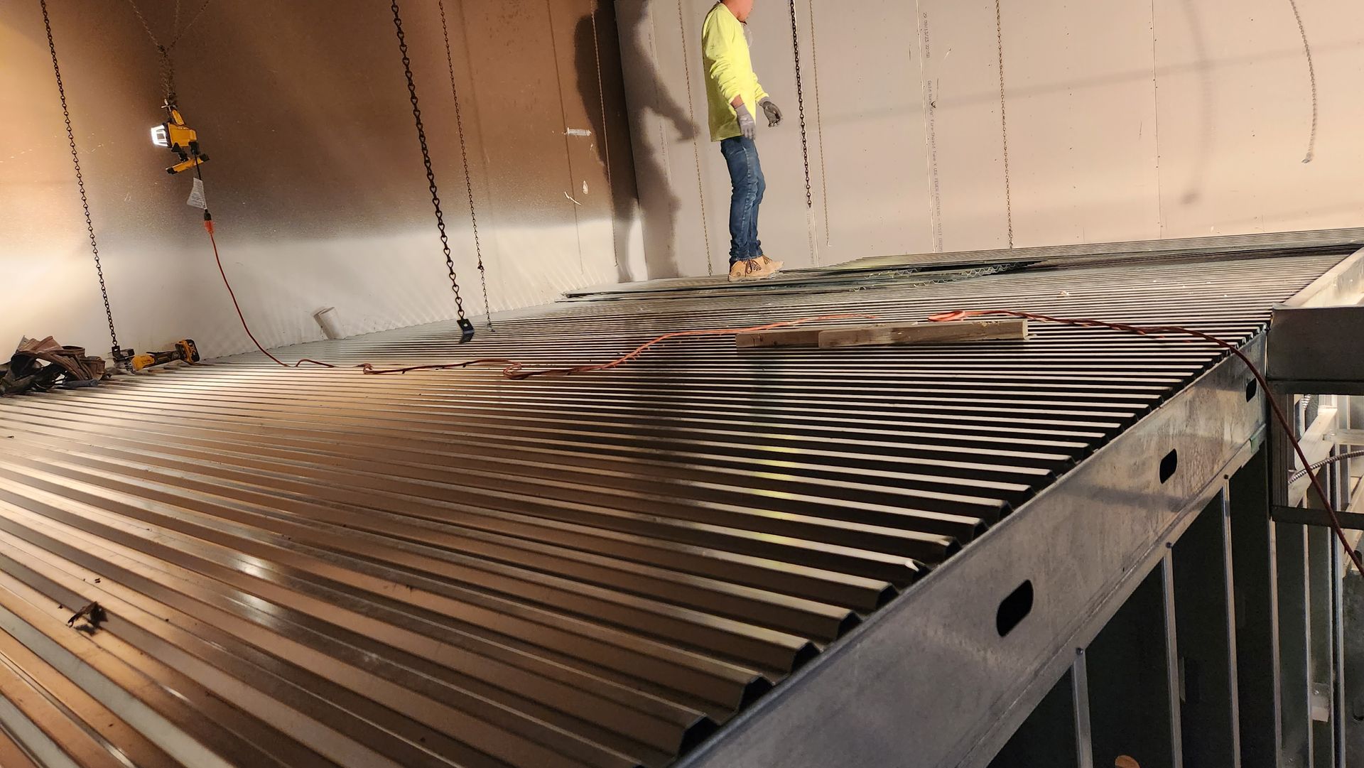 Worker standing inside a large metal tank with wiring. Interior view.