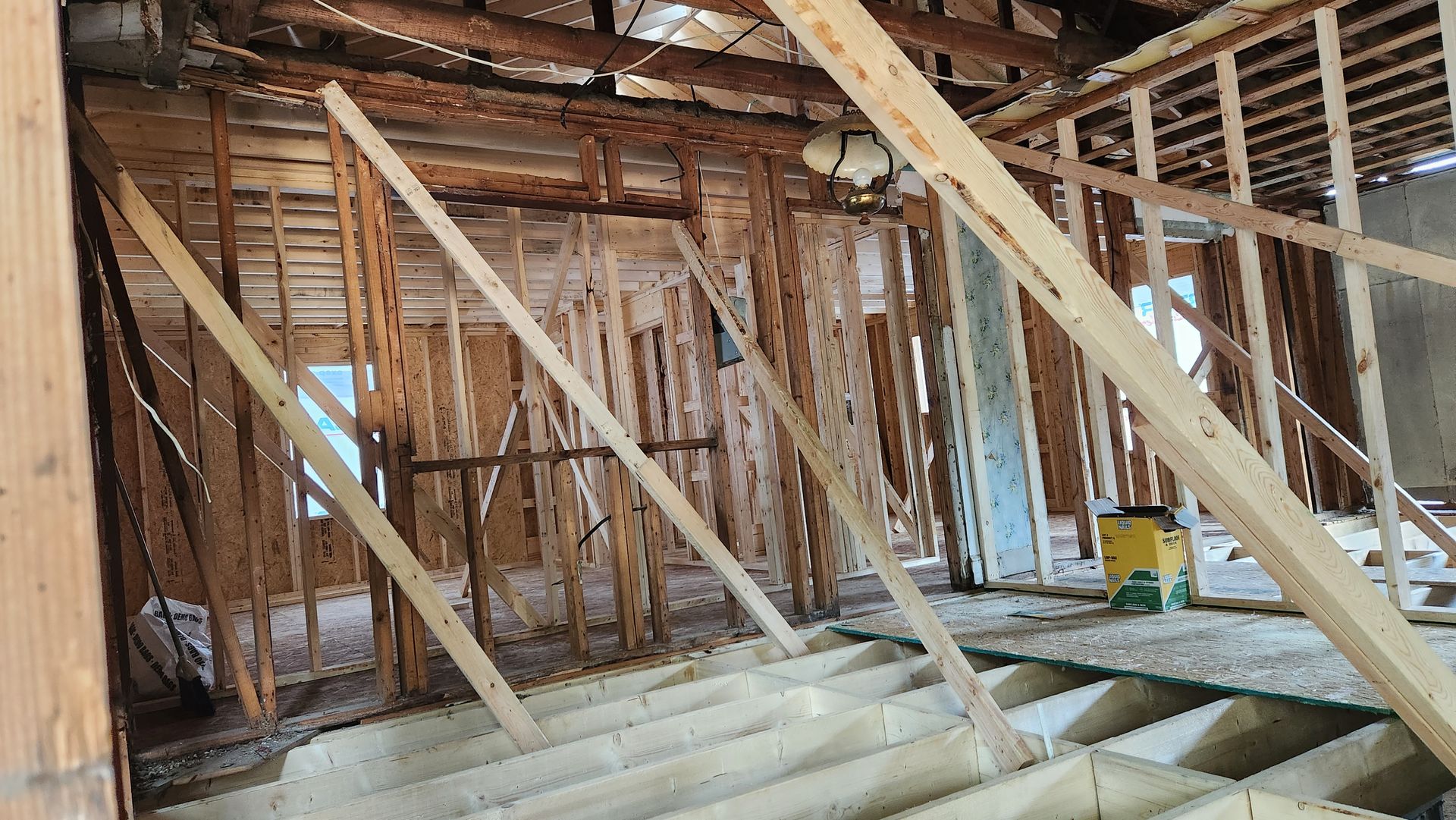 Interior of a building under renovation, showing exposed wooden framing and support beams.