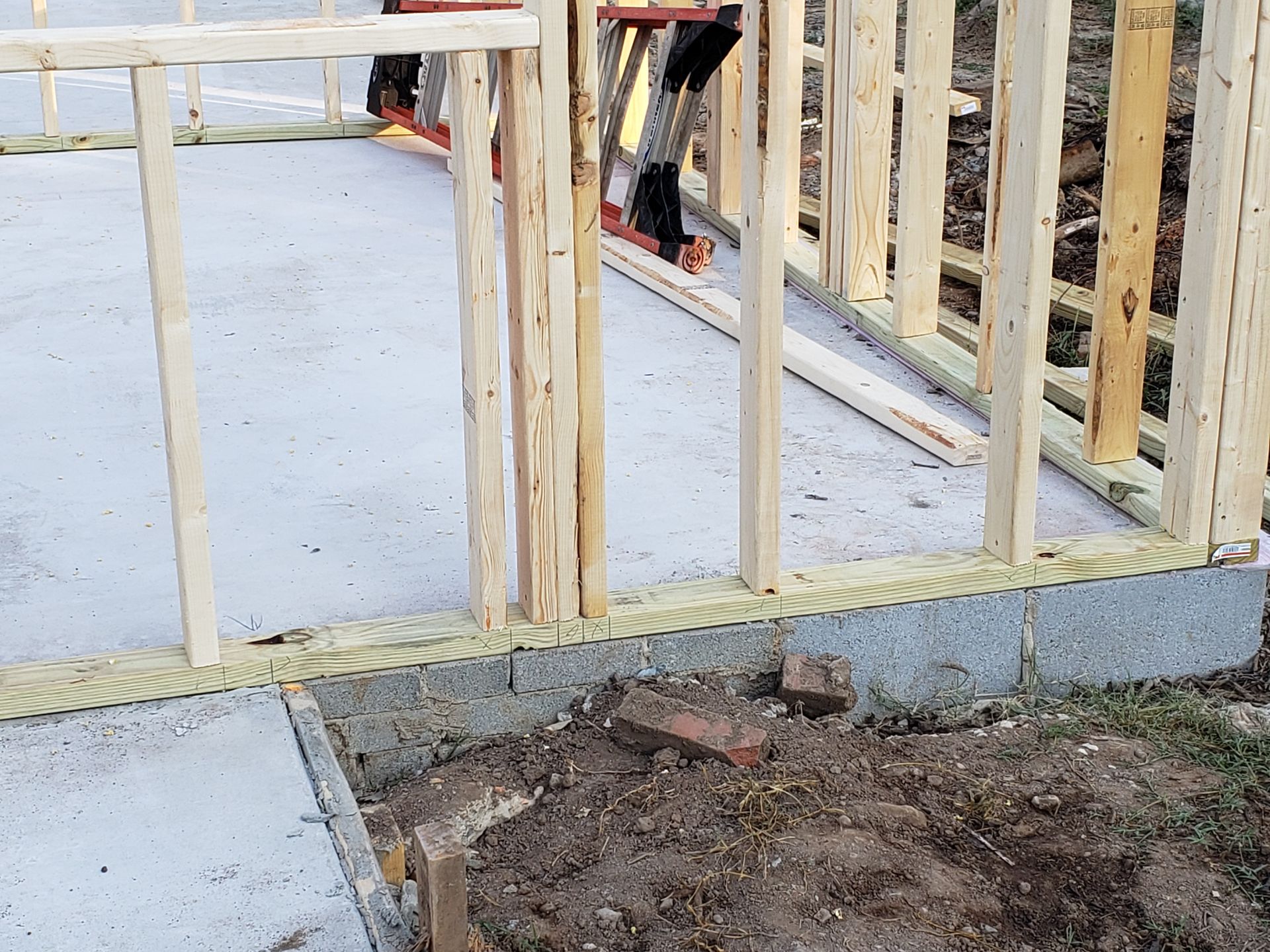 Wooden framing of a building under construction on a concrete foundation; close up view.