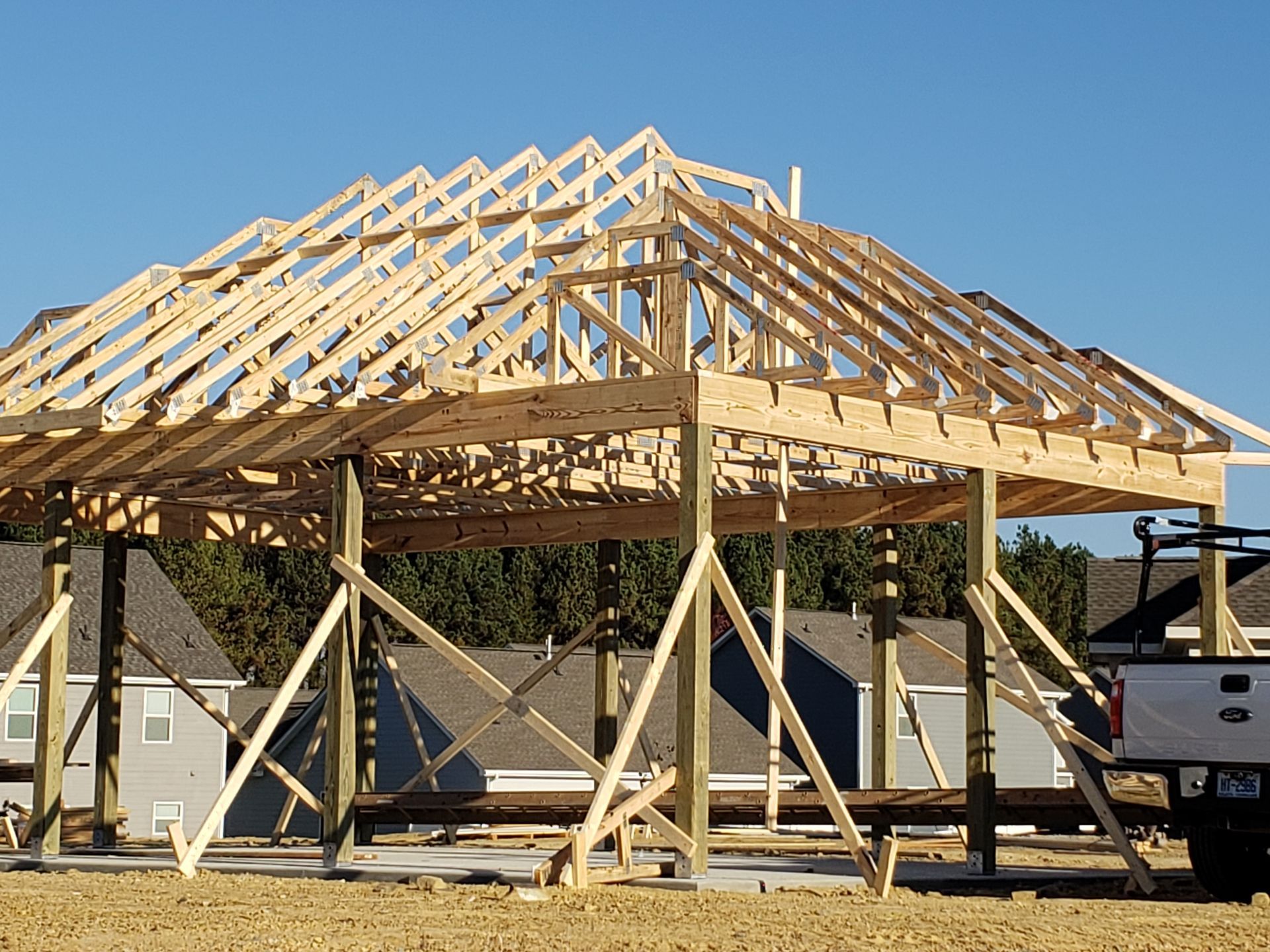 Wooden frame of a building under construction, supported by temporary braces, with a clear blue sky.