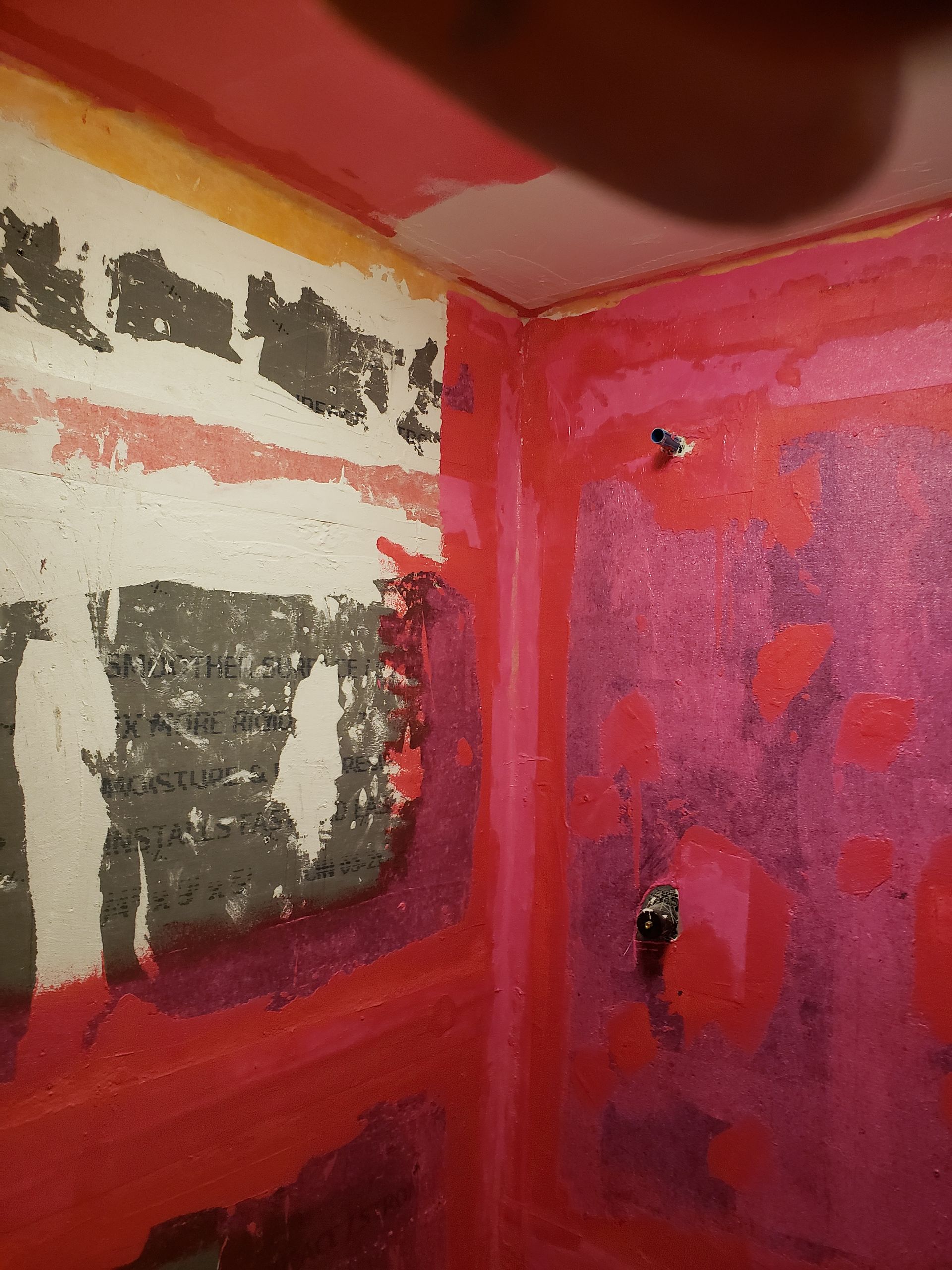 Shower stall with pink waterproofing membrane and exposed cement board.