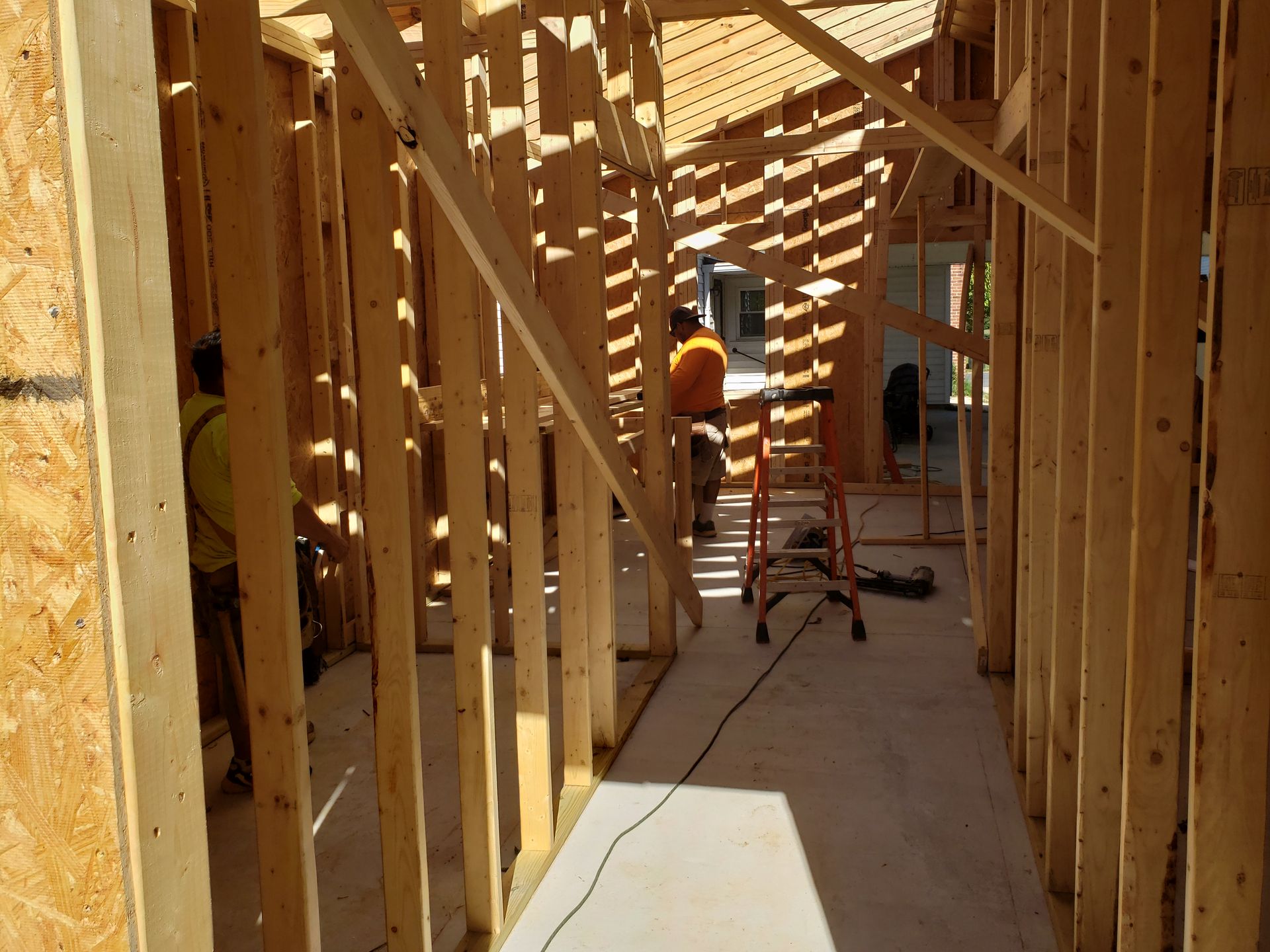 Interior view of a building under construction, showing wooden framing and workers.