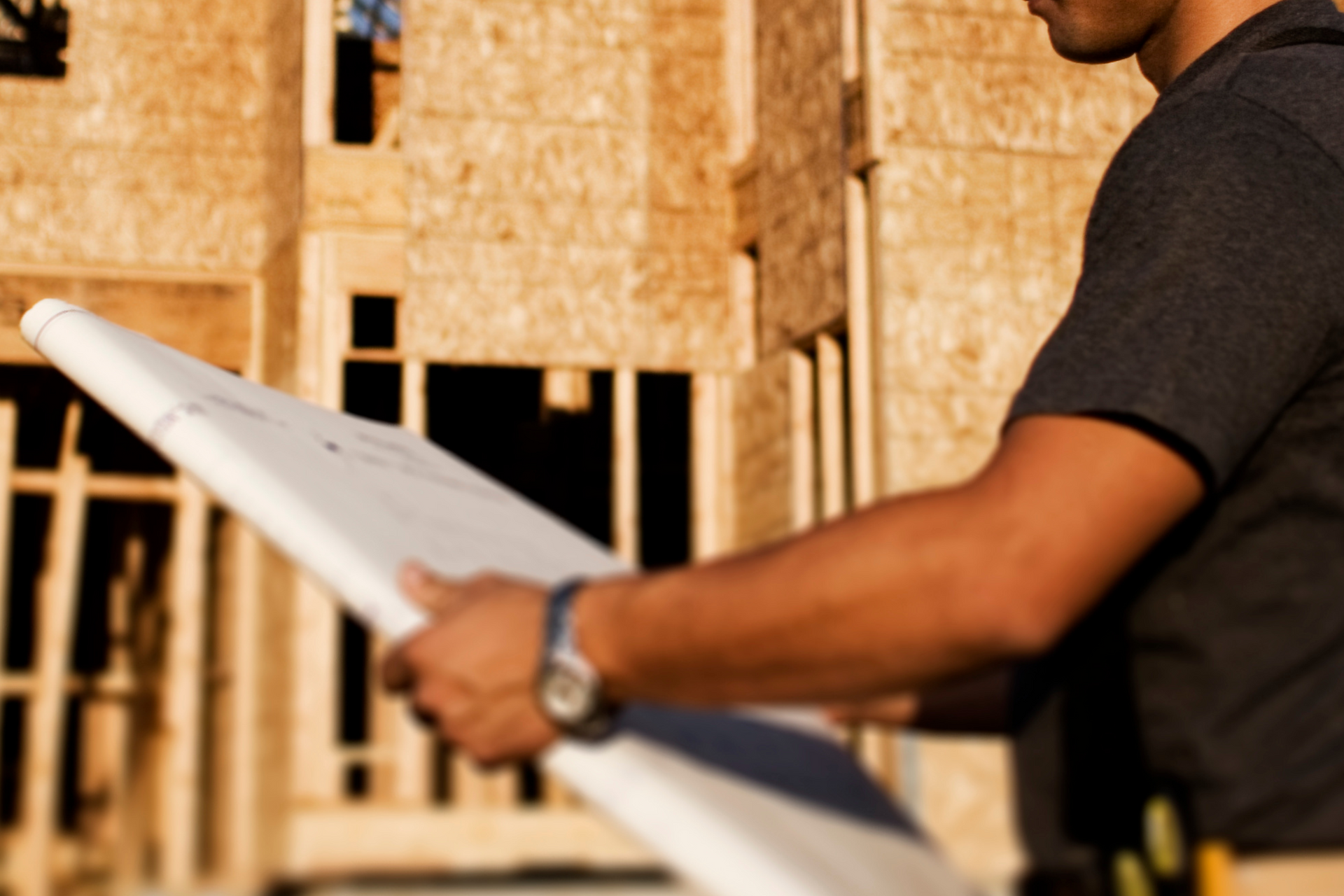 General contractor reviewing blueprints on-site during custom home construction planning phase.