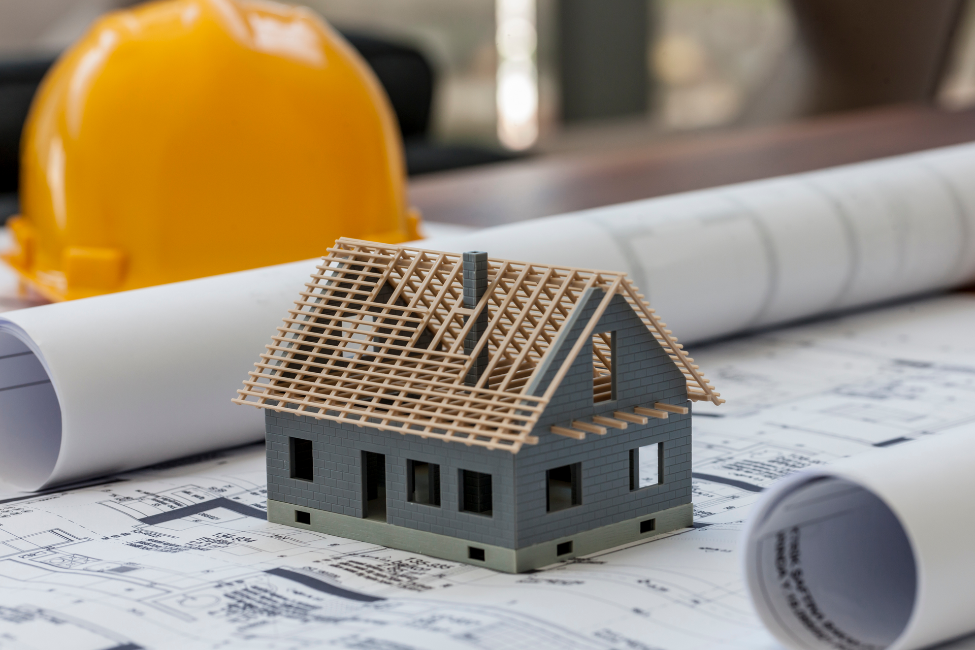 Model home displayed on blueprints representing custom home construction planning and general contracting.