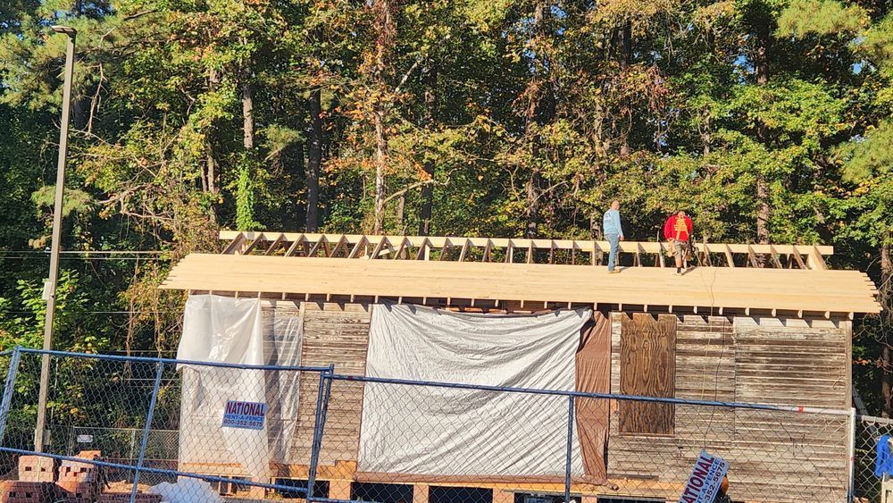 General contractors performing roof work during full home renovation of aged wood-frame structure.