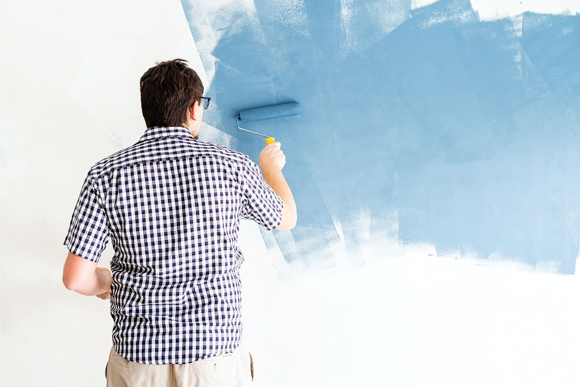 a man painting a wall with blue paint