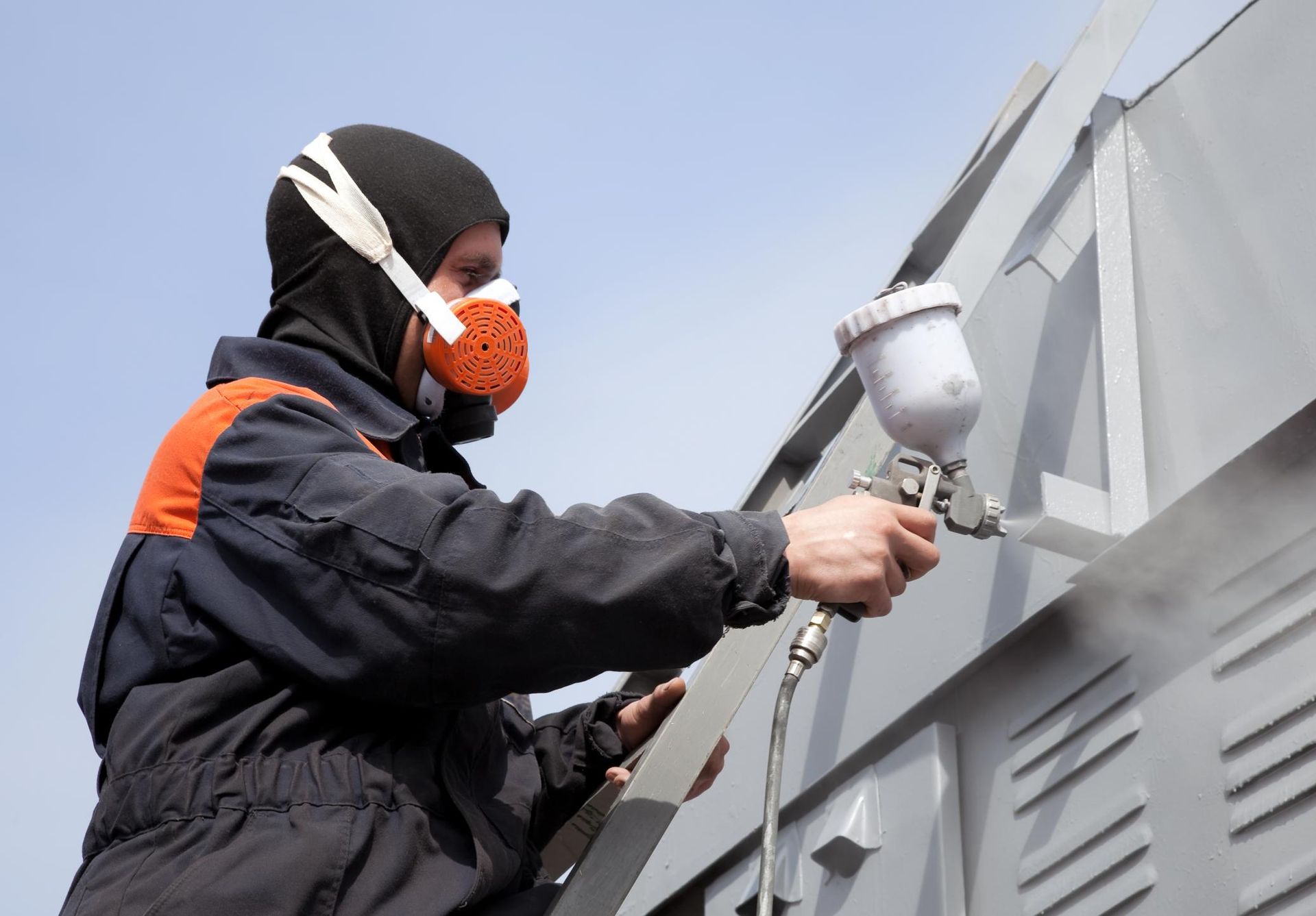 a man in a black jacket spray painting a building