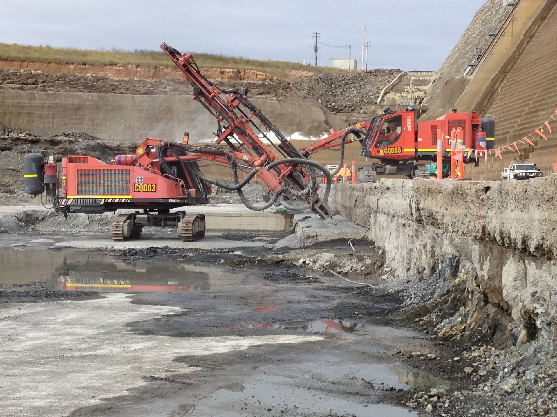 A large red excavator is working on a construction site