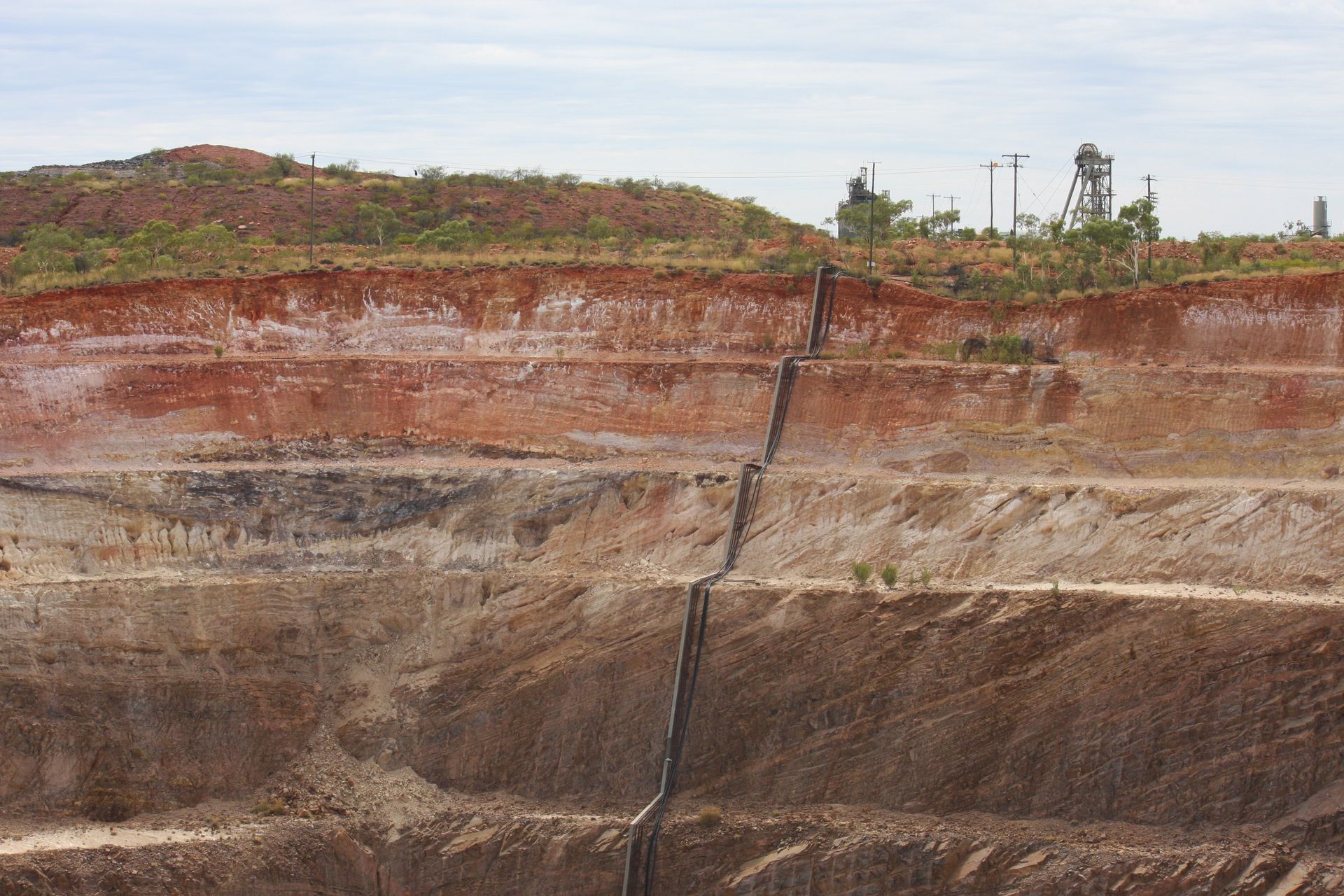 A large pile of dirt and rocks with a water tower in the background.