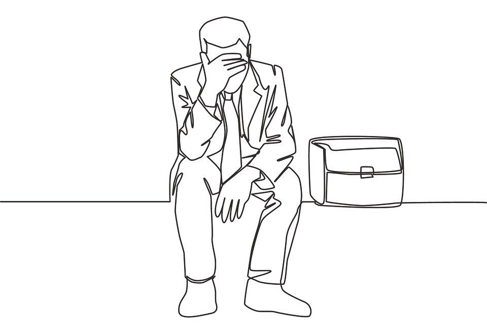 Un uomo in giacca e cravatta è seduto su una panchina con la testa tra le mani.