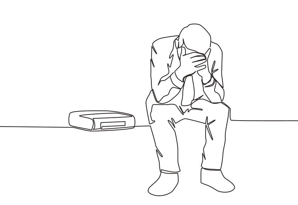 Un uomo in giacca e cravatta è seduto a terra con la testa tra le mani.