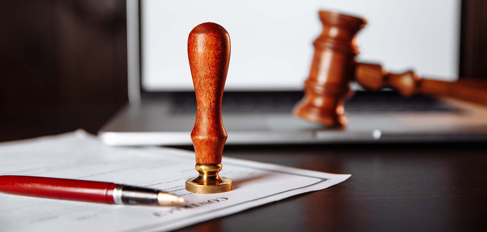 A wooden stamp is sitting on top of a piece of paper next to a pen.