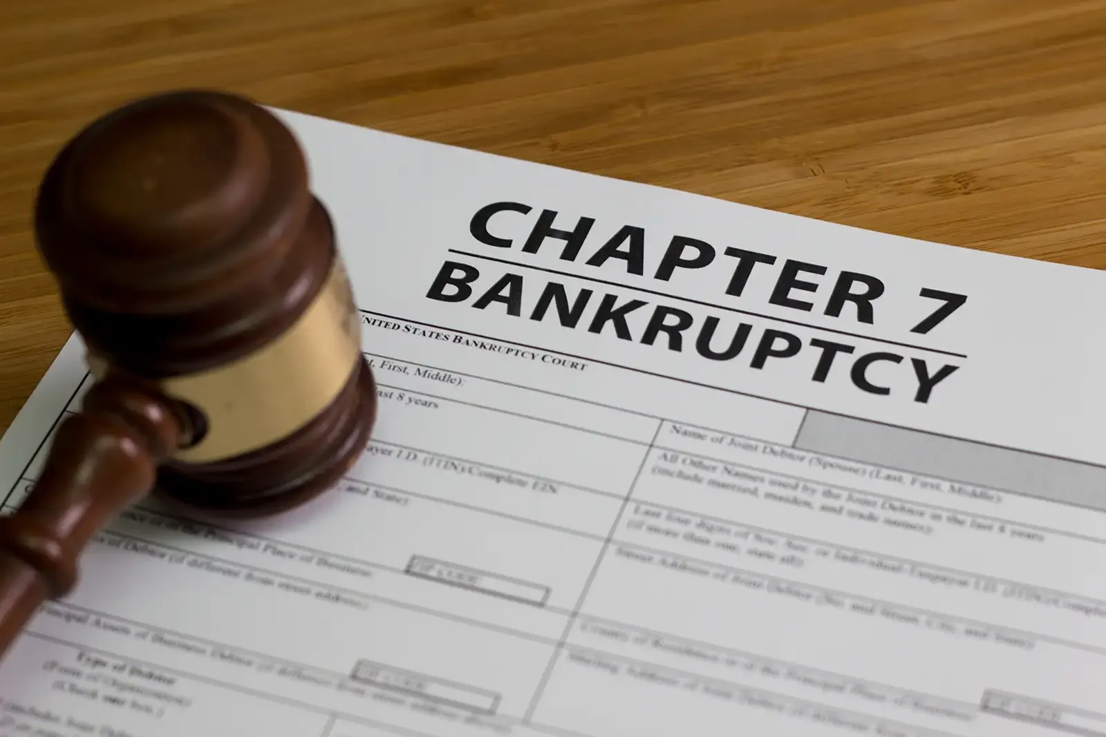 A wooden gavel is sitting on top of a chapter 7 bankruptcy form