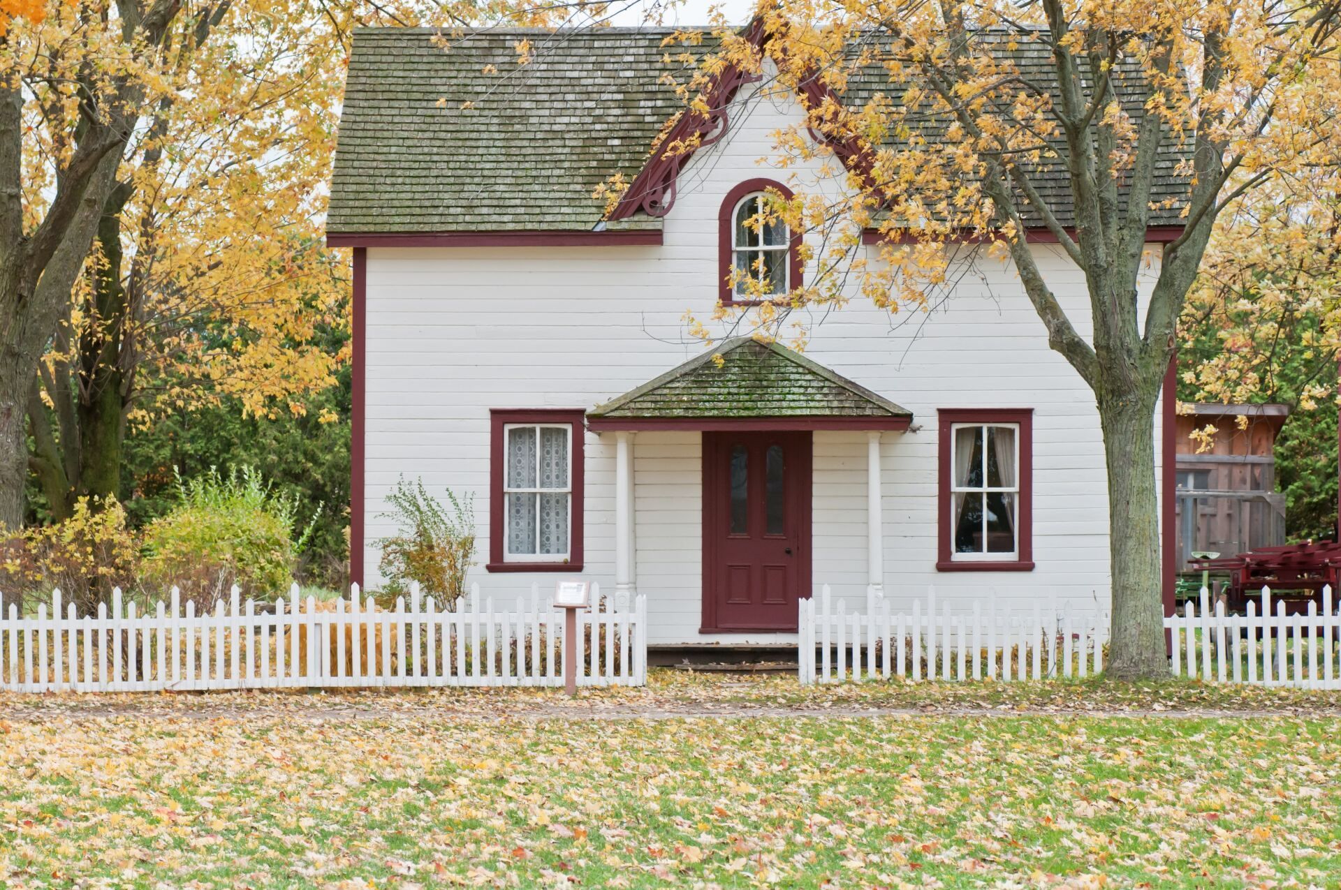 A white house with a red door and a white picket fence.