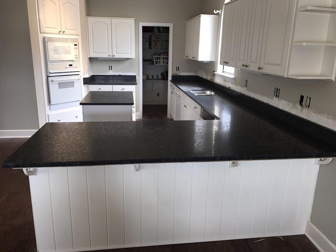 A kitchen with black counter tops and white cabinets