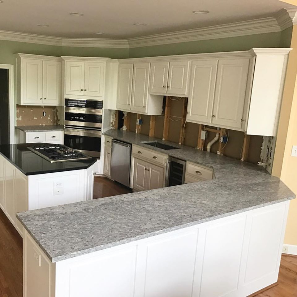 A kitchen with white cabinets , granite counter tops , and stainless steel appliances.