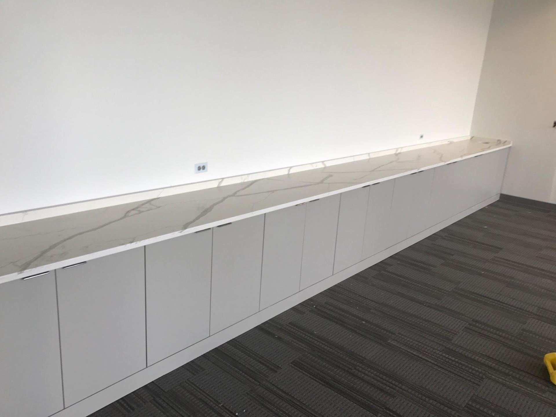 A long white cabinet with a marble counter top in a room.