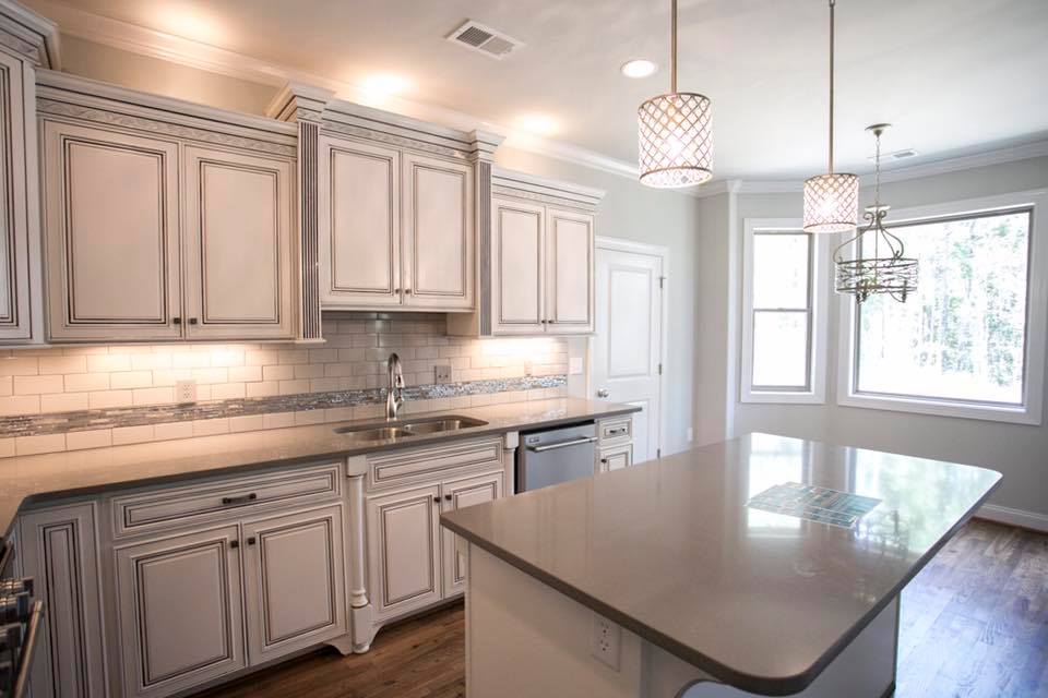 A kitchen with white cabinets , granite counter tops , and a large island.