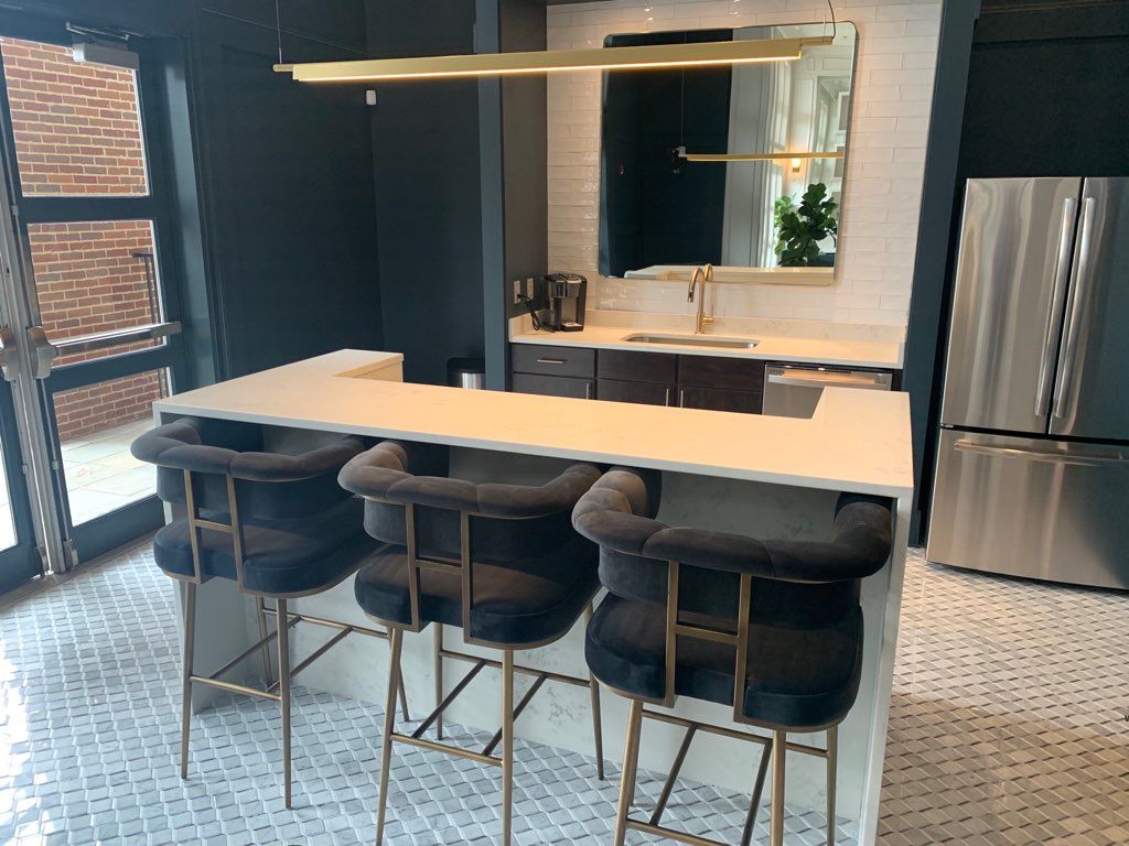 A kitchen with a bar and stools and a stainless steel refrigerator.