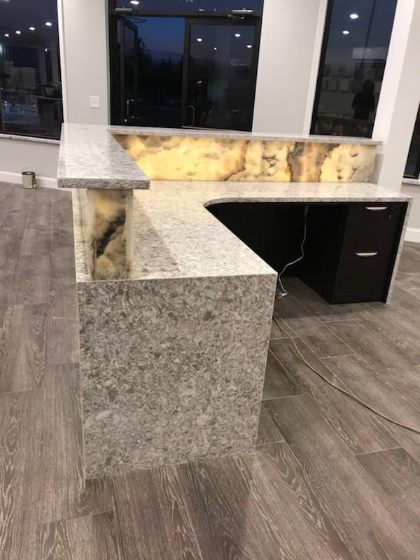 A kitchen with a granite counter top and a wooden floor.