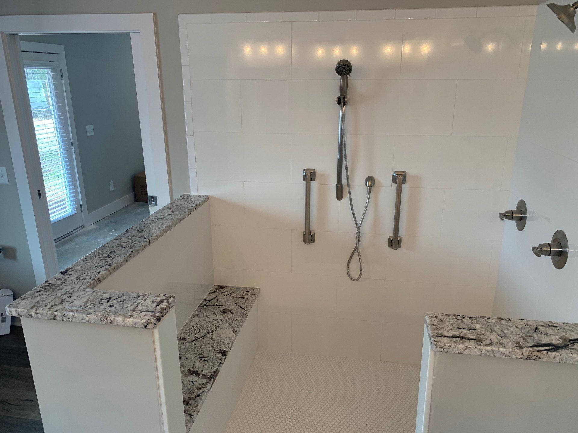 A bathroom with a walk in shower and a bench.