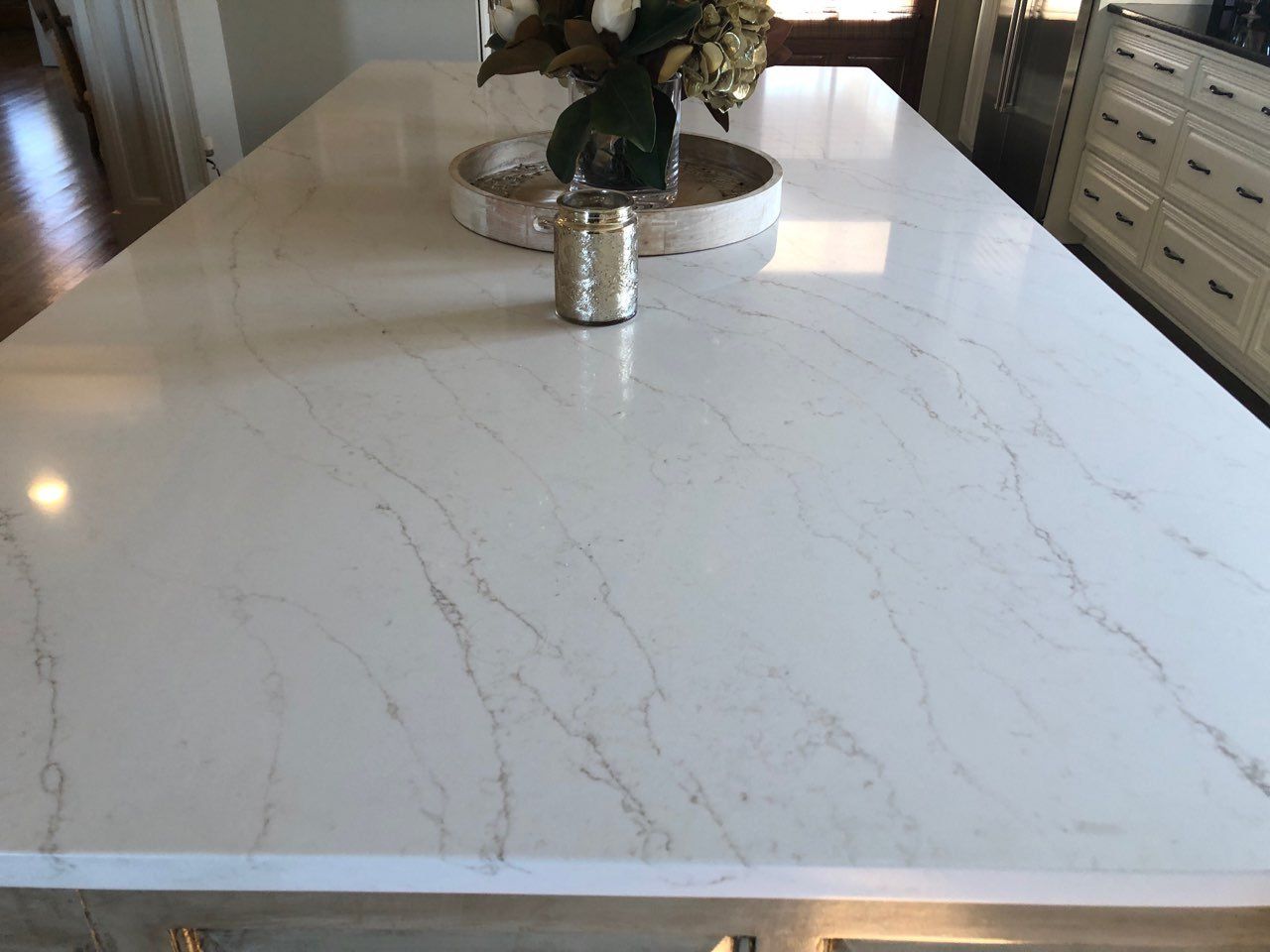 A white marble counter top with a vase of flowers on it.
