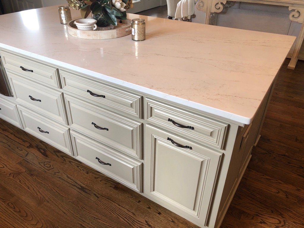 A kitchen island with white cabinets and a white counter top.