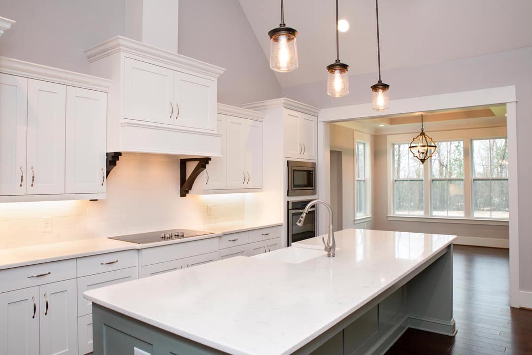 A kitchen with white cabinets and a large island in the middle.