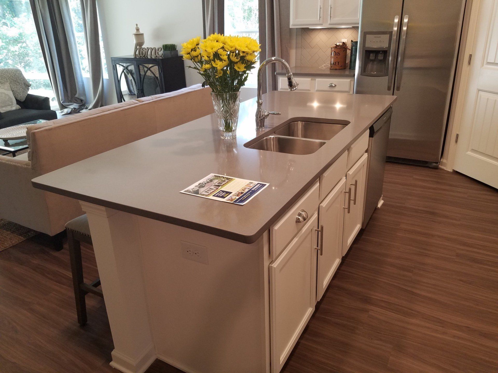 A kitchen with a sink and a vase of yellow flowers on the counter.