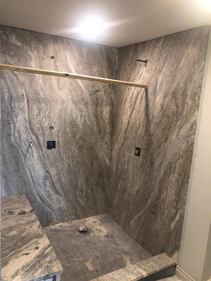 A bathroom with a walk in shower and marble walls.