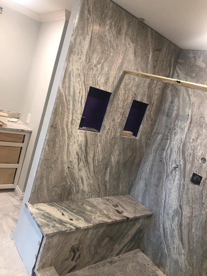 A bathroom with a walk in shower and a bench.