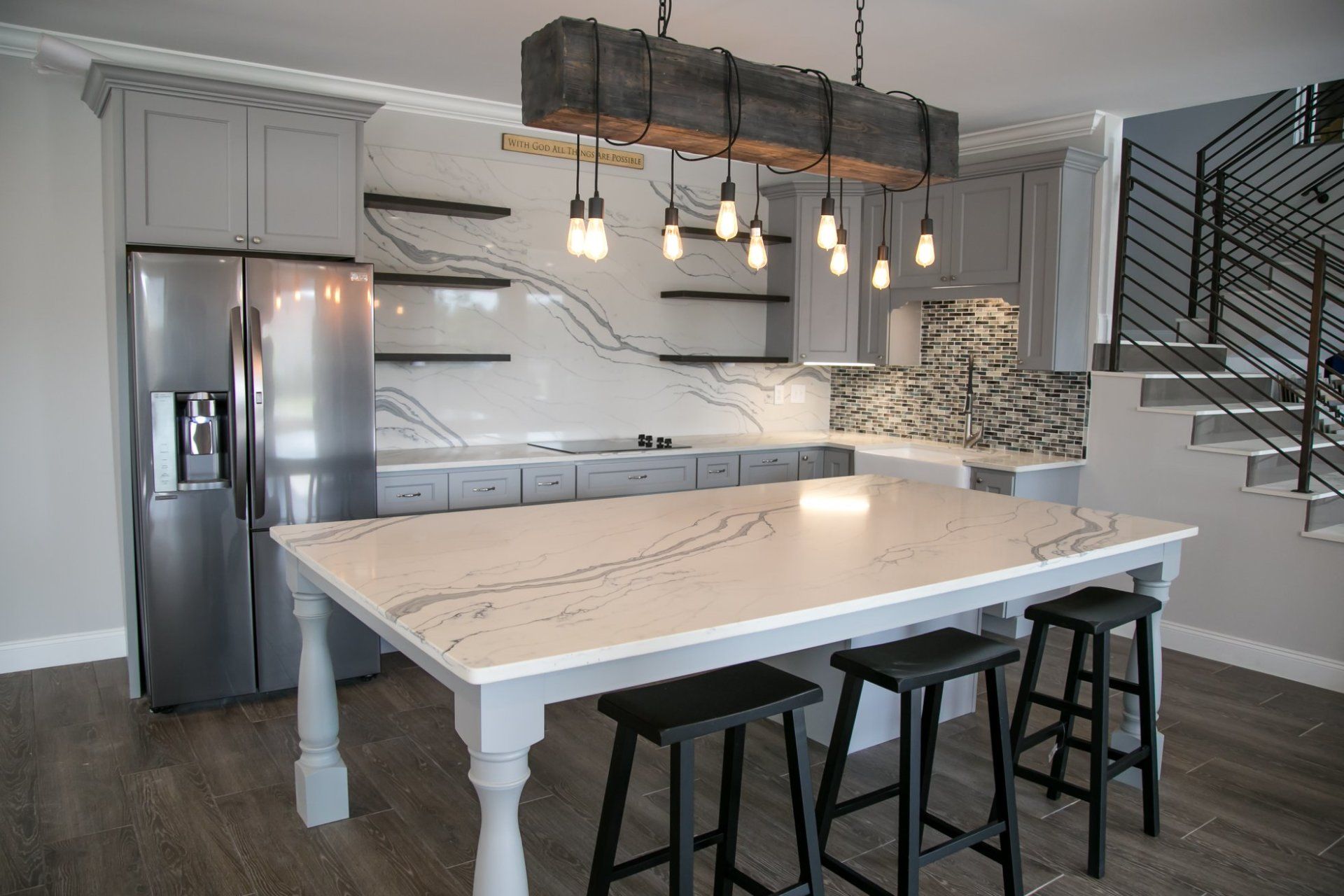 A kitchen with a large table and stools and a refrigerator.