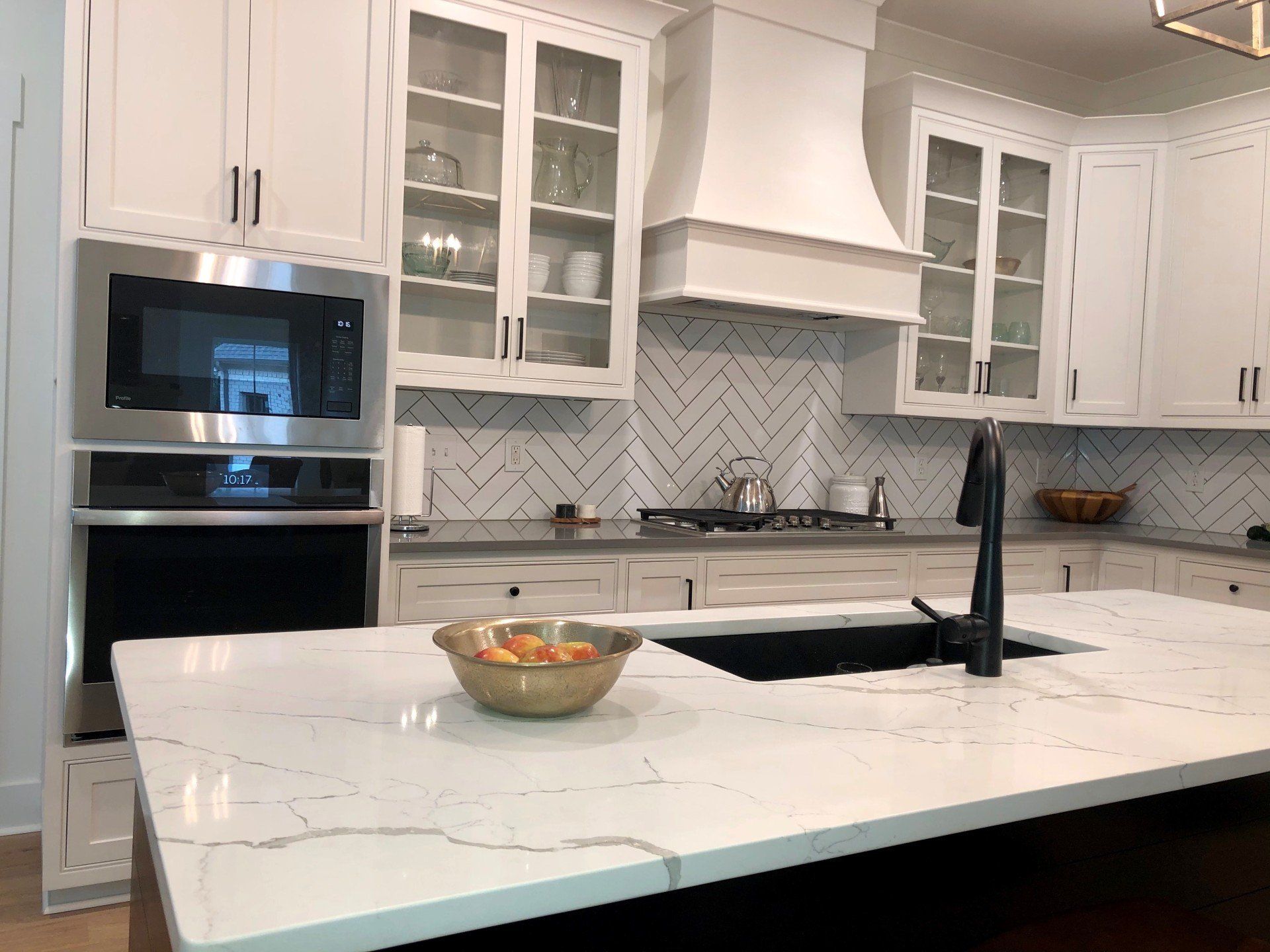 There is a bowl of fruit on the counter in the kitchen.