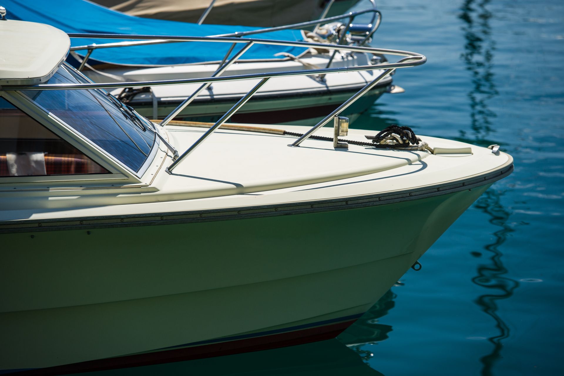 White boat bow with silver railing in blue water.