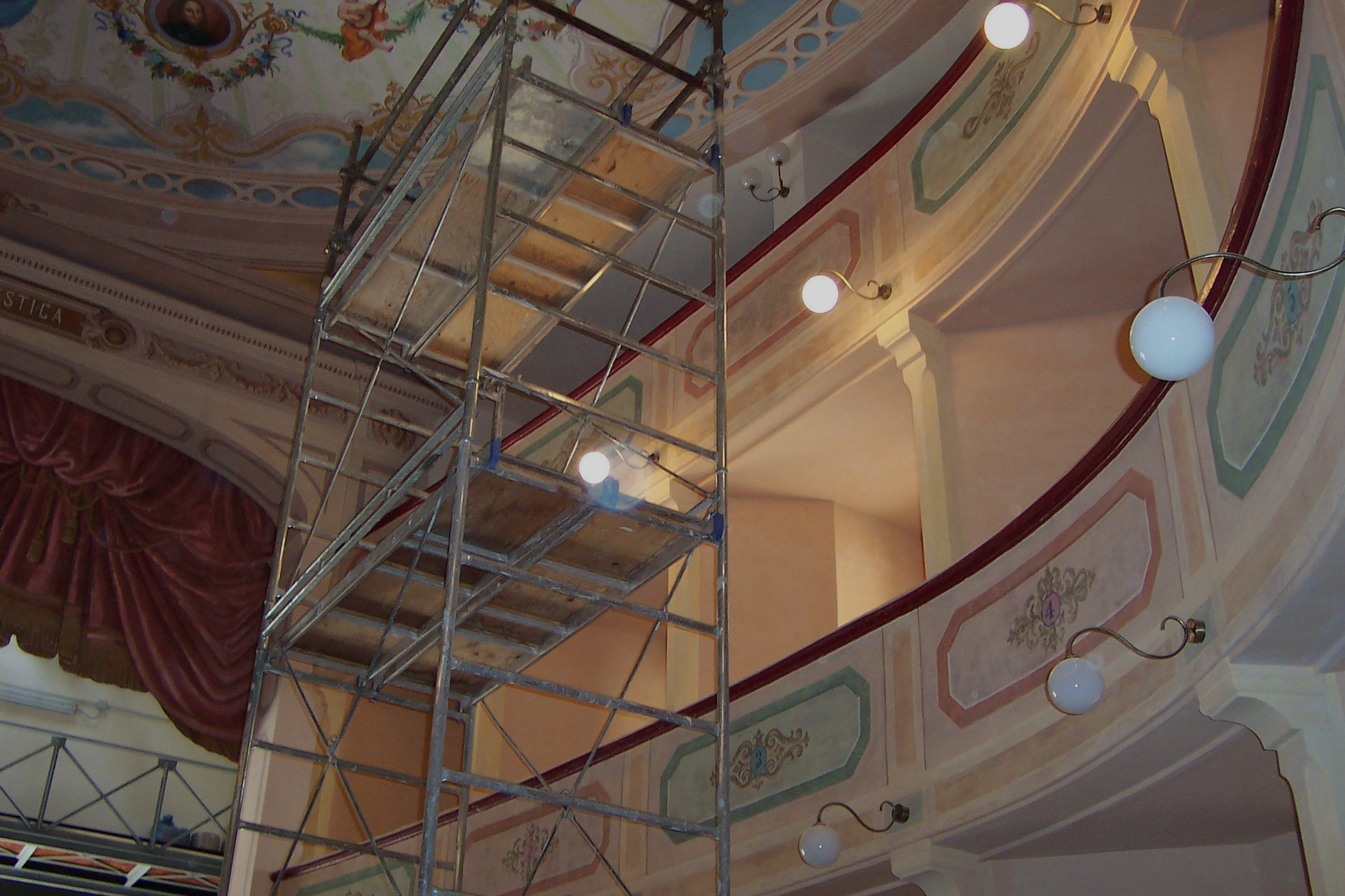 Impalcature all'interno di un teatro con pareti decorate e luci durante i lavori di ristrutturazione.