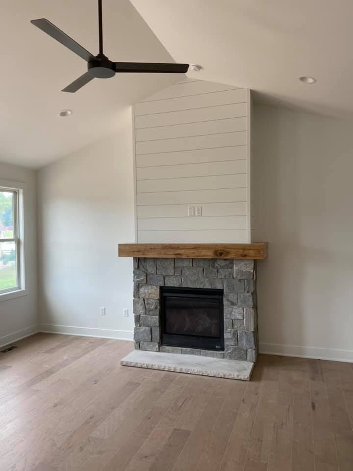 A living room with a fireplace and a ceiling fan.