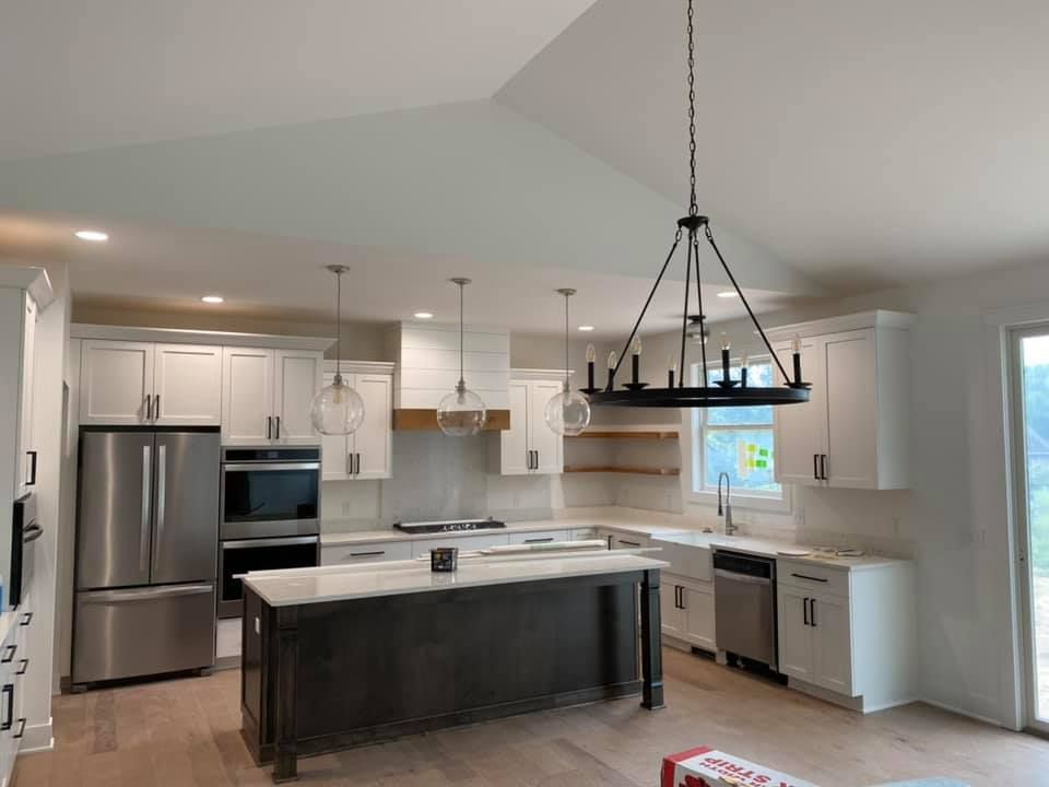 A kitchen with white cabinets , stainless steel appliances , and a large island.