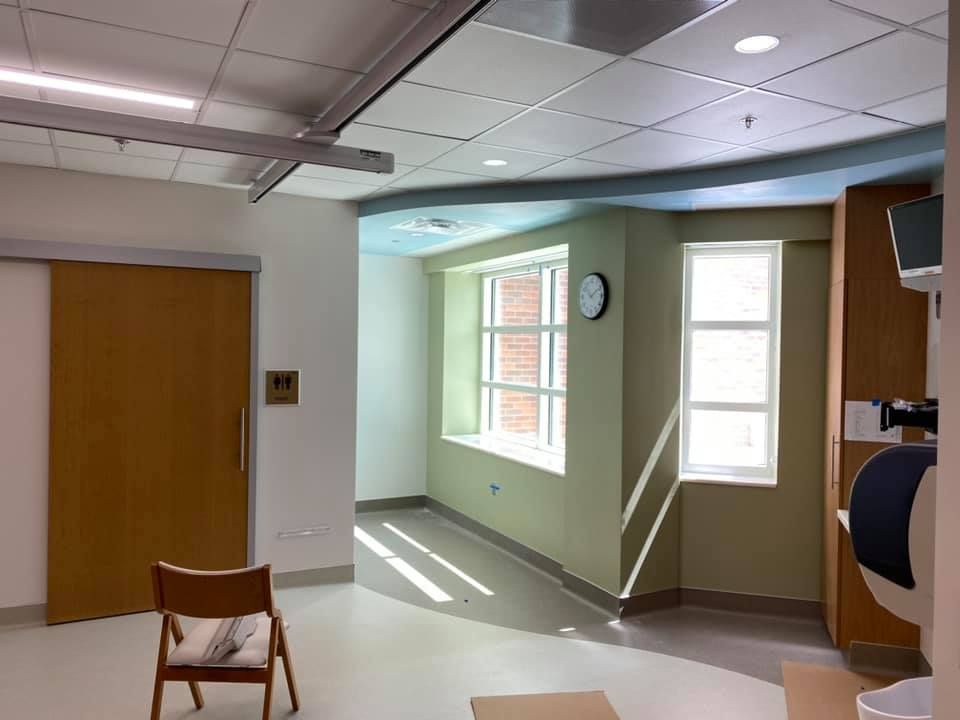 A hospital room with a chair and a clock on the wall