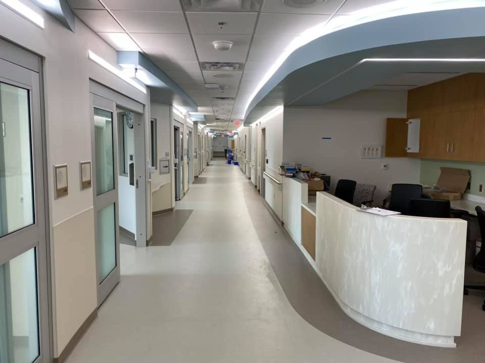 A long hallway in a hospital with a reception desk in the middle.