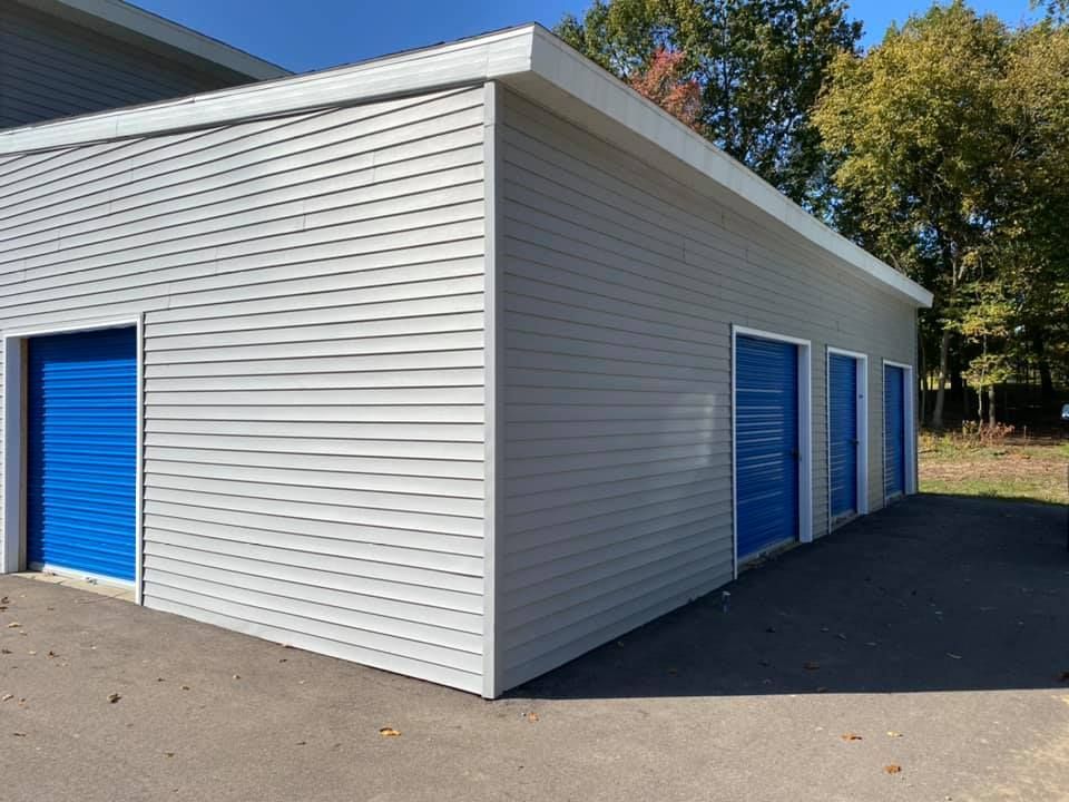 A white building with blue doors is sitting in a parking lot.