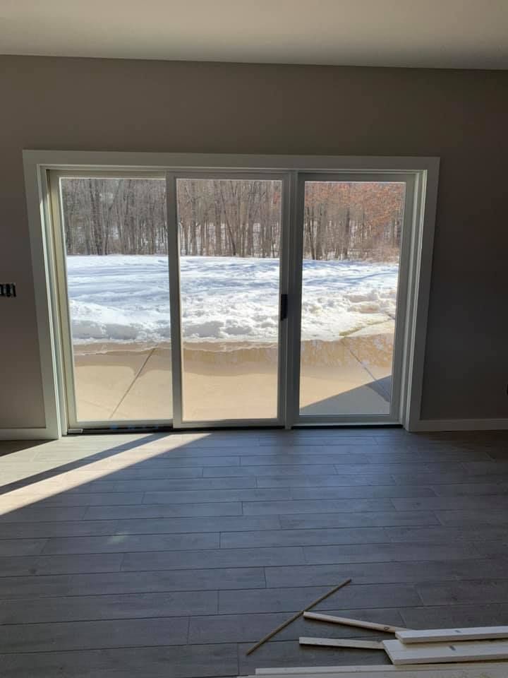 An empty room with a sliding glass door and a view of a snowy forest.
