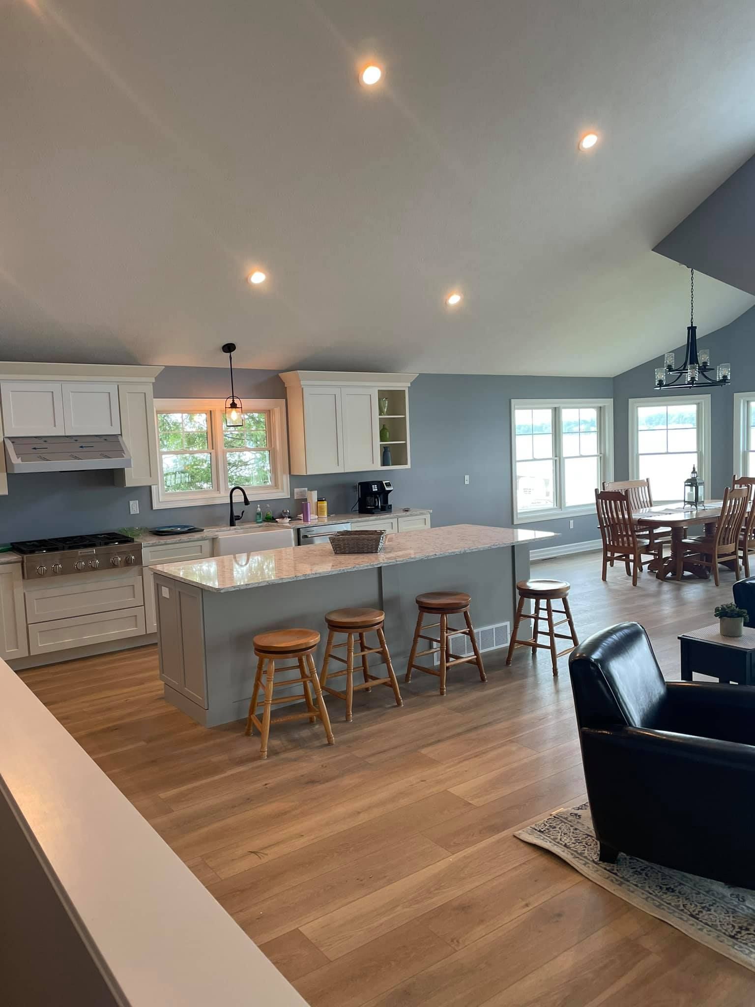 A kitchen with a large island and stools in a living room.